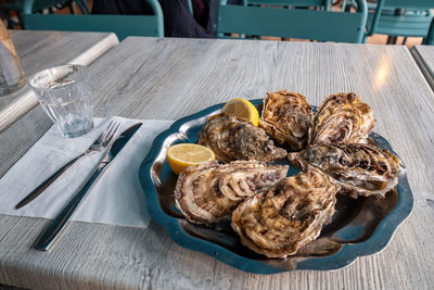 Fresh oysters on blue plate, with lemon and ice. healthy seafood