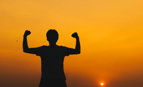 Silhouette man standing against orange sky during sunset