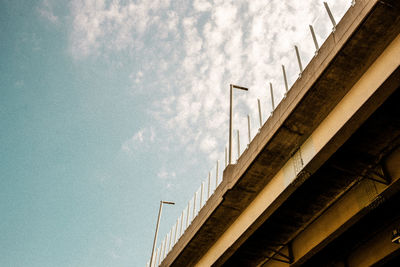 Low angle view of bridge by building against sky