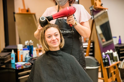 Hairdresser wearing flu mask drying hair of client in salon