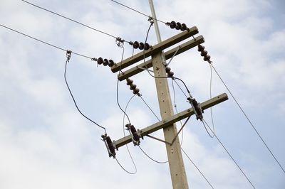 Low angle view of cables and pole against sky