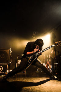 Man playing guitar at illuminated stage