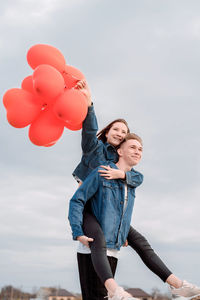 Valentines day. young loving couple hugging and holding red heart shaped balloons outdoors