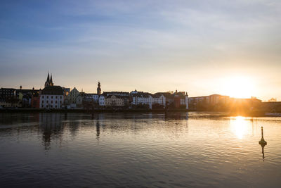 View of buildings at waterfront during sunset