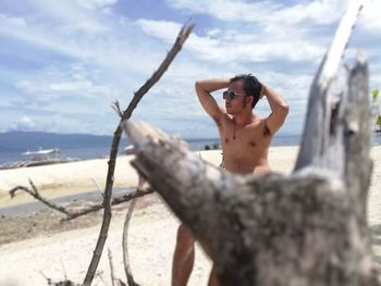 Young man standing on beach against sky