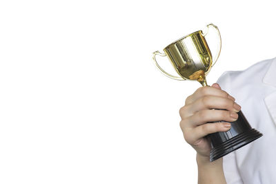 Close-up of hand holding trophy against white background