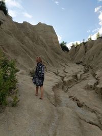 Rear view of woman standing on mountain against sky