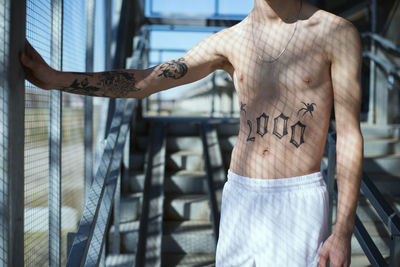 Midsection of shirtless man with tattoo