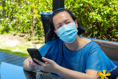 Midsection of man holding mobile phone while sitting outdoors