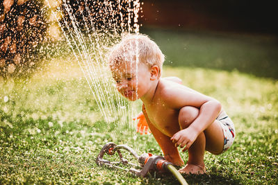 Full length of shirtless boy splashing water