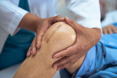 Midsection of doctor holding patients knee