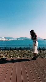 Side view of teenage girl on pier with sea and cruise in background