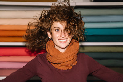 A fashion designer joyfully twirls in her studio, her curly hair animatedly capturing the motion