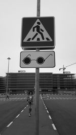 Road sign on street in city against sky