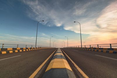 Surface level of highway against sky during sunset