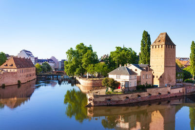 Buildings by river against clear sky