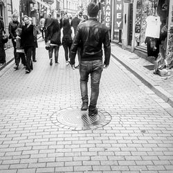 Rear view of people walking on footpath in city