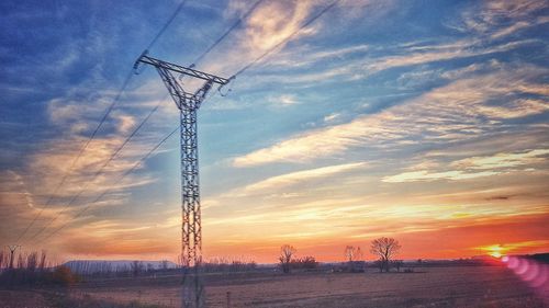 Low angle view of electricity pylon against dramatic sky