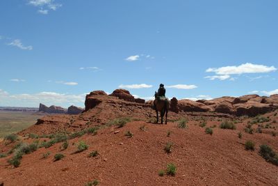 Rear view of person riding horse at desert