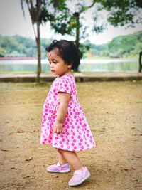 Cute baby girl looking away while standing outdoors