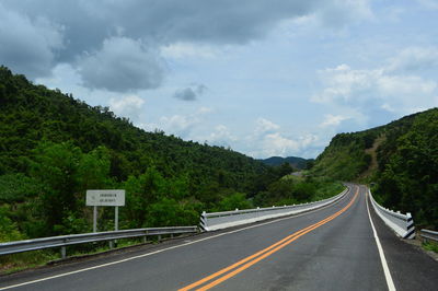 Road leading towards mountains against sky