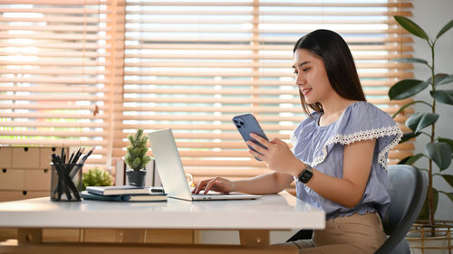 Young woman using mobile phone while sitting on sofa at home