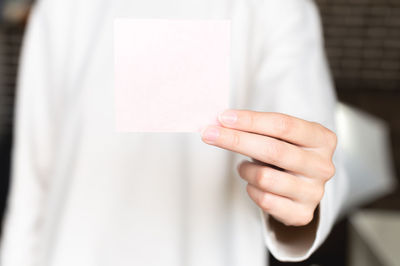 Woman is holding a square empty blank sticker in her hands. background space for text or advertising