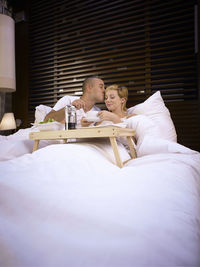 Man kissing woman on bed in hotel room