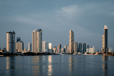 River by modern buildings in city against sky