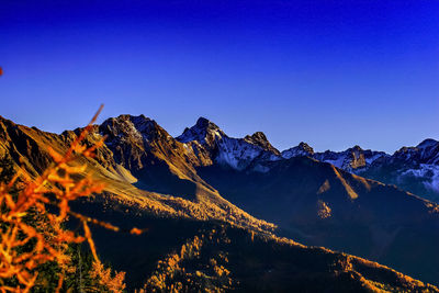 Scenic view of snow covered mountains against clear blue sky