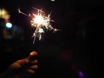 Cropped hand holding sparkler at night