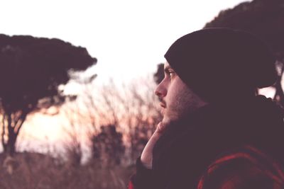 Young man looking away against sky