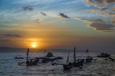 Silhouette sailboats in sea against sky during sunset