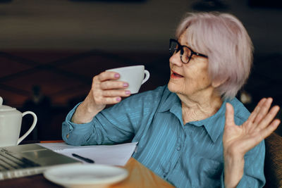 Smiling senior woman holding coffee cup at cafe