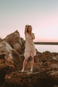 Woman standing on rock against sky