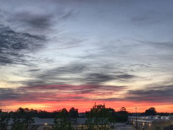 Silhouette trees and buildings against sky during sunset