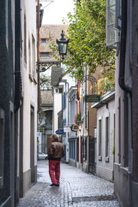 Rear view of woman walking on street amidst buildings