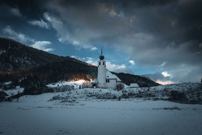 Church against mountain range and sky during winter