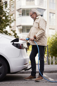 Senior man charging electric car