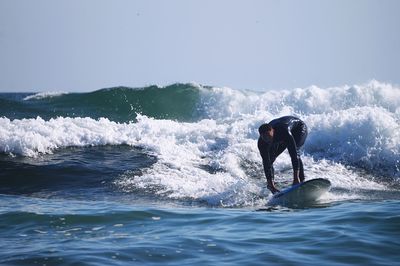 Man surfing in sea against sky