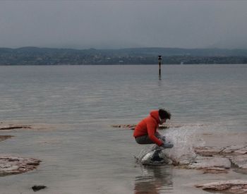 Man working in sea against sky