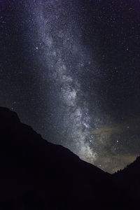 Low angle view of silhouette mountain against sky at night