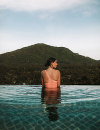 Man relaxing in swimming pool against mountain