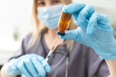 Midsection of doctor holding syringe against white background