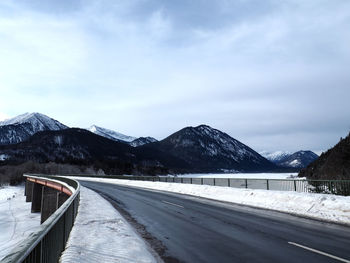 Road and mountains against cloudy sky during winter