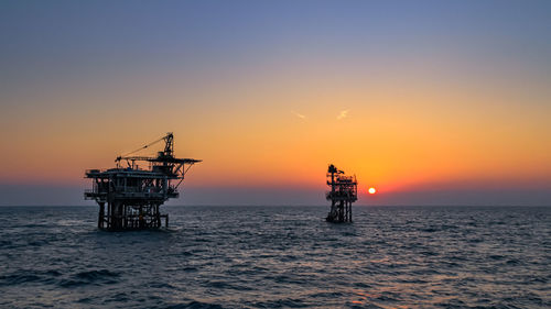 Silhouette ship in sea against sky during sunset