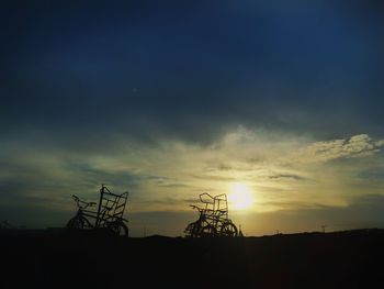 Silhouette of electricity pylon against sky during sunset