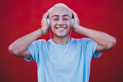 Young man with headphones against red background