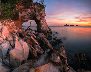 Rock formation on beach against sky during sunset