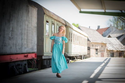Portrait of woman walking on railroad station platform by train